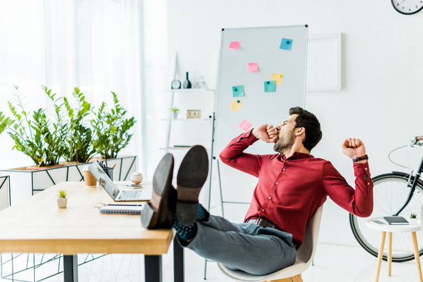 empresário cansado com pernas na mesa bocejando no escritório
 - Foto, Imagem