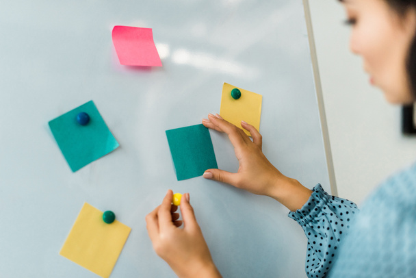 cropped view of woman putting colorful sticky notes on white board in office - Photo, Image