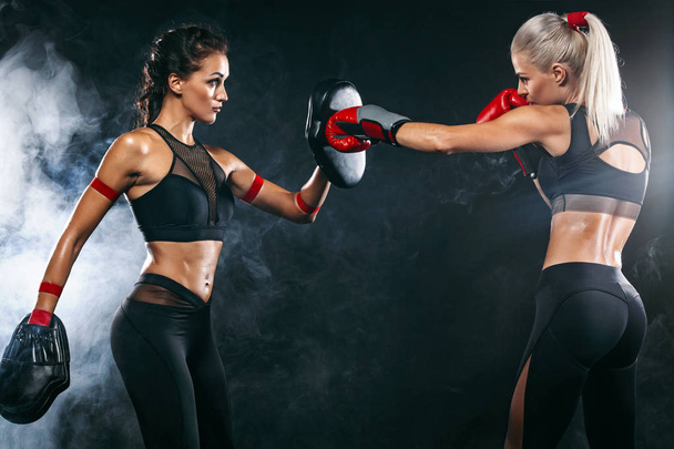 Two women athlete and boxer trainging before fight on black background. Sport and boxing concept. - Foto, imagen