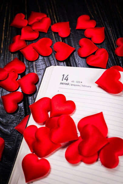 Valentine's Day and the concept of holidays - close-up of a calendar sheet with the date February 14, and many red hearts - Photo, Image