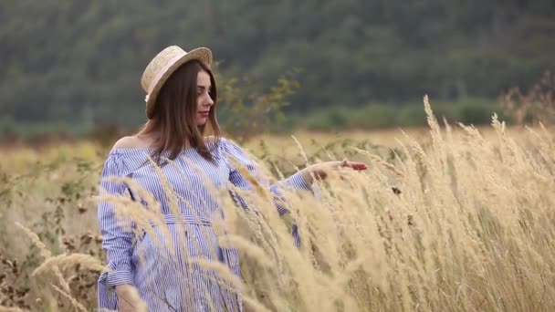 La mujer embarazada en la naturaleza se prueban el sombrero de punto. Antecedentes de campo y fachada blanca cerca de la granja. montañas
 - Imágenes, Vídeo