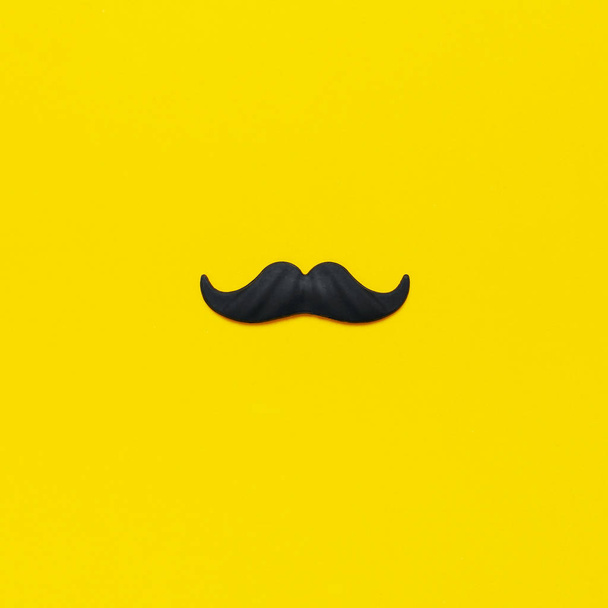 Black mustache, props for photo booths, carnival, parties on yellow background top view flat lay copy space. Father's day, Creative party decoration concept. Men's health awareness month. - Photo, Image