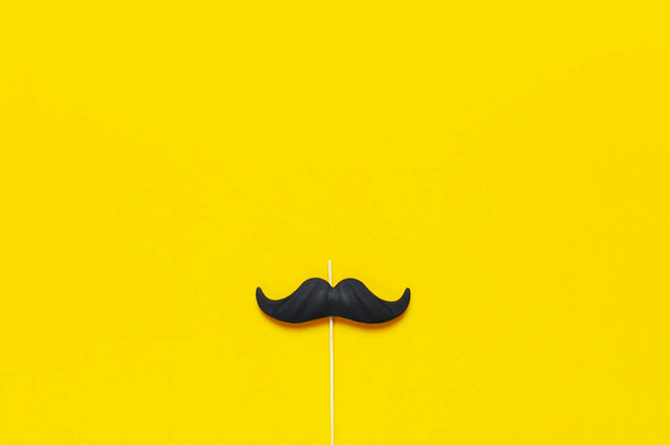 Black mustache, props for photo booths, carnival, parties on yellow background top view flat lay copy space. Father's day, Creative party decoration concept. Men's health awareness month. - Photo, Image