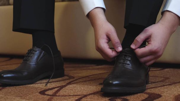 man ties up his shoelaces on his black shoes - Φωτογραφία, εικόνα