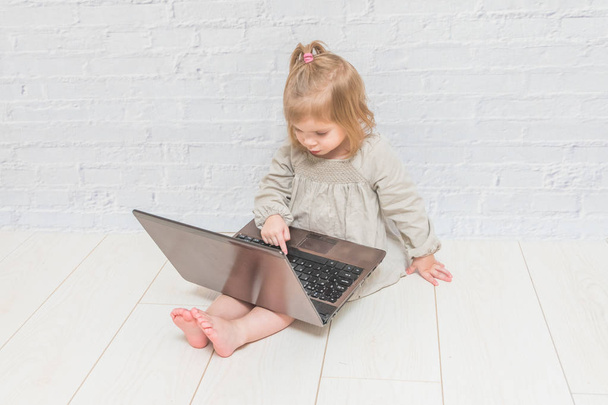 girl, child businesswoman working at a laptop, against a white brick wall - Foto, Imagem