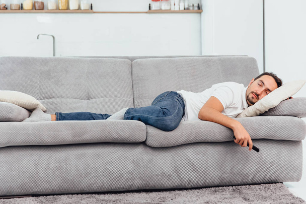 The man fell asleep on the couch holding the remote - Fotoğraf, Görsel