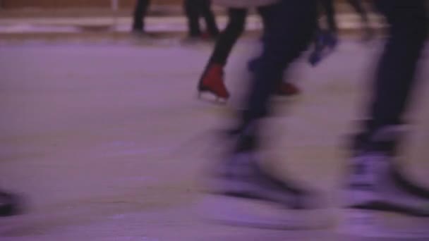 Άνθρωποι πατινάζ στο παγοδρόμιο του εξωτερική. Σκέιτερ πάγου τη νύχτα του χειμώνα. Εορτασμός της Πρωτοχρονιάς και Χριστουγέννων. Δείτε και τα πόδια. - Πλάνα, βίντεο