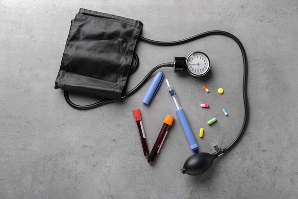 Sphygmomanometer, blood samples, pills and insulin syringe on grey background. Health care concept - Photo, Image