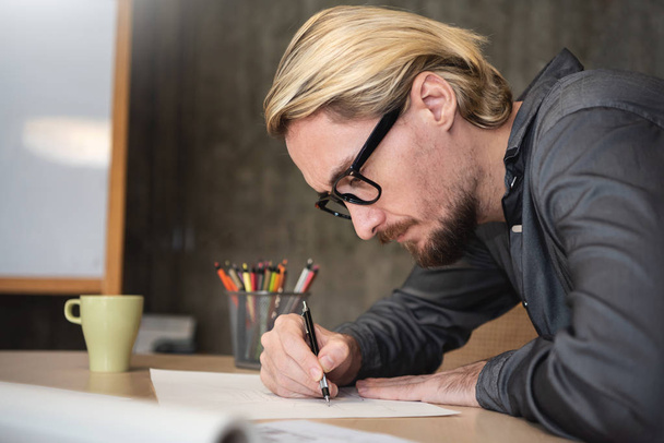 Designer Masculino usa óculos trabalhando com novo projeto de inicialização no escritório ou café
.  - Foto, Imagem