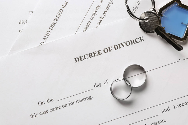 Anelli con decreto di divorzio e chiave da casa su tavolo. Concetto di divisione della proprietà coniugale
 - Foto, immagini