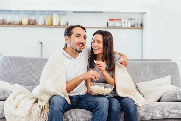A woman and husband wandering the TV while sitting on the couch - Foto, Bild