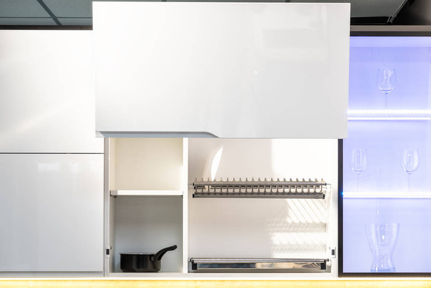komplett geöffneter weißer Küchenschrank mit Tellern und Gläsern im Regal - Foto, Bild