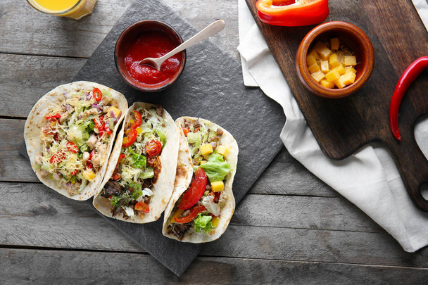 Tasty tacos with sauce on wooden table - Foto, afbeelding