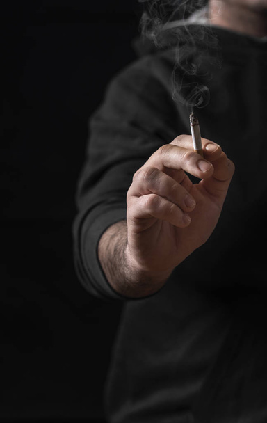 Männersilhouette mit einer brennenden Zigarre vor der Kamera. Raucherentwöhnung. Wenig Licht Rauchen Kontext. Rauchstopp. - Foto, Bild