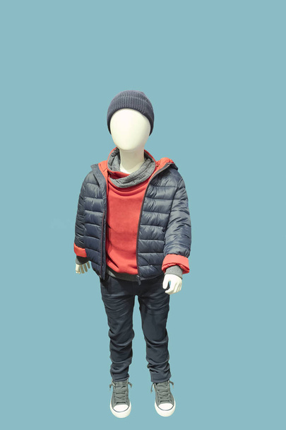 Full-length child mannequin dressed in fashionable kids wear, isolated on blue background. No brand names or copyright objects. - Photo, Image