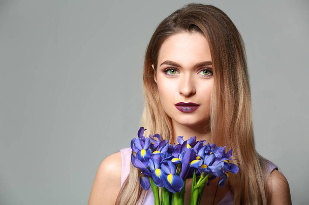 Beautiful young woman with bouquet of flowers on grey background - Zdjęcie, obraz