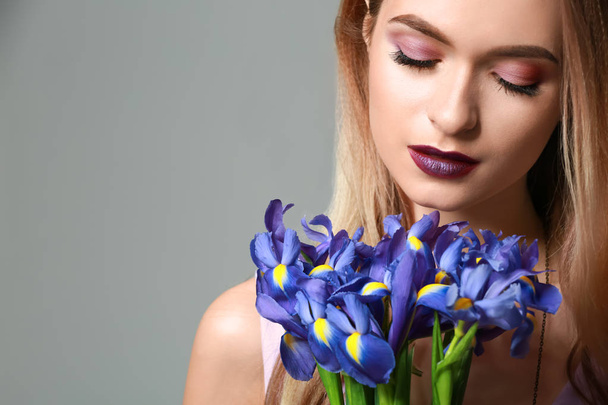 灰色の背景の上に花の花束と美しい若い女性 - 写真・画像