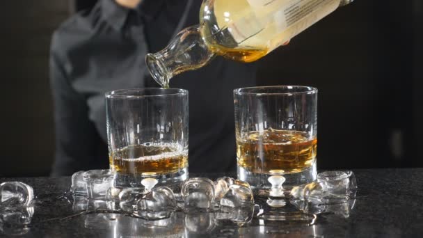 an der Theke. Unerkennbare Barkeeperin in schwarzem Hemd, die in Zeitlupe Whiskey in Jigger gießt. Cocktail machen Konzept.. hd - Filmmaterial, Video