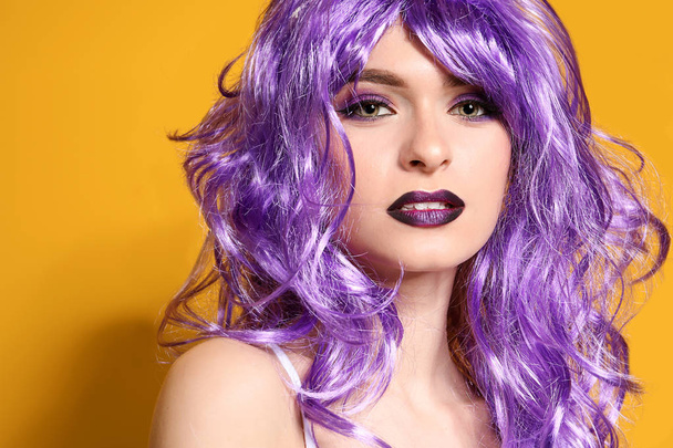 Beautiful young woman with violet wig on color background - Fotó, kép