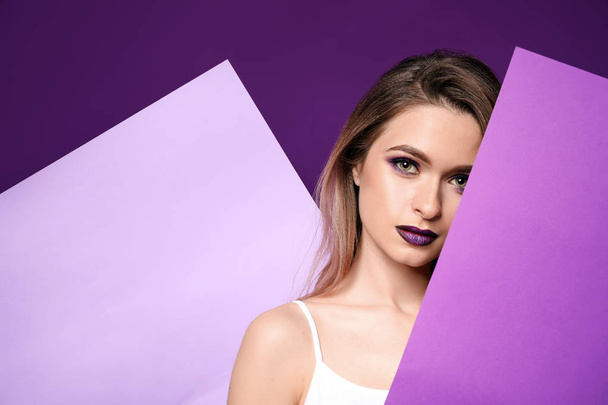 Beautiful young woman with blank posters on violet background - 写真・画像