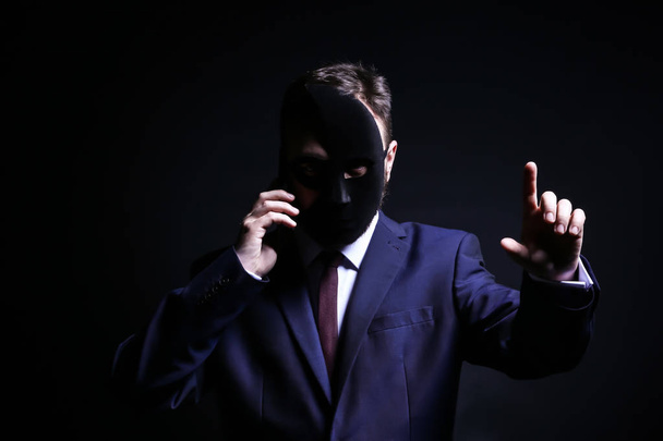 professionelle Hacker mit Handy auf dunklem Hintergrund. Konzept des Internethandels - Foto, Bild
