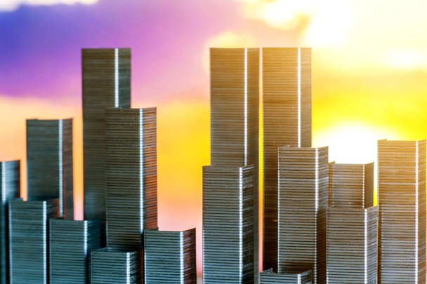 grapas dispuestas para formar el horizonte de la ciudad sobre un fondo de puesta de sol
 - Foto, Imagen