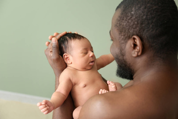 Feliz padre afroamericano con bebé en el interior
 - Foto, imagen