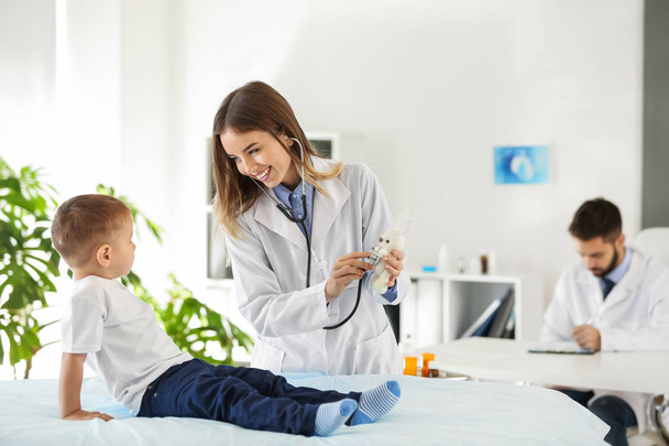 Γυναίκα γιατρό εργασίας με χαριτωμένο μικρό αγόρι στην κλινική - Φωτογραφία, εικόνα
