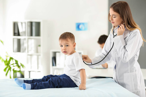 Female doctor working with cute little boy in clinic - Photo, Image