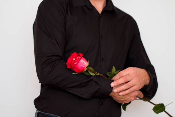 Un homme en chemise noire avec une fleur dans les mains
 - Photo, image