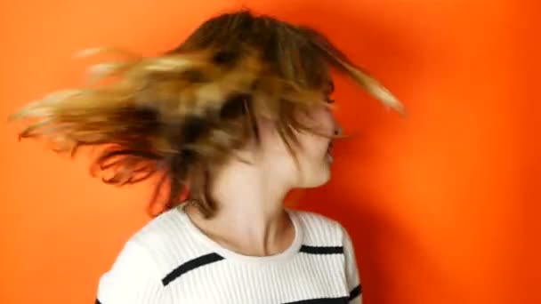 Teenager waving her hair on a coral background - Imágenes, Vídeo