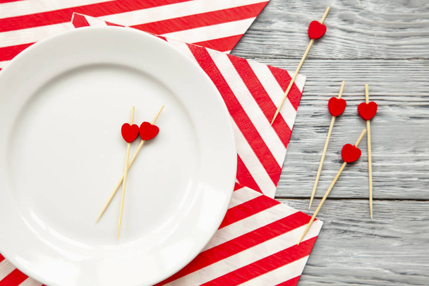 Twee tandenstokers met kleine rode hartjes op witte plaat en vele tothpicks op een gestreepte feestelijke servet. Concept van een verjaardag of vakantie - Foto, afbeelding