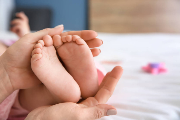 Moederdag handen aanraken van kleine voeten van kleine baby, close-up - Foto, afbeelding