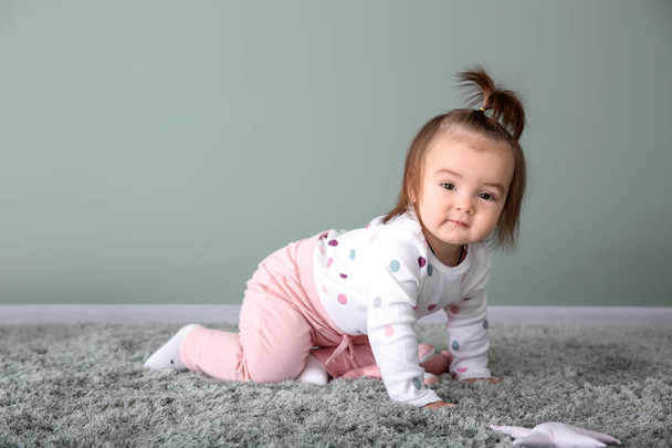 Χαριτωμένο μωρό κορίτσι στο χαλί κοντά σε χρώμα τοίχου - Φωτογραφία, εικόνα