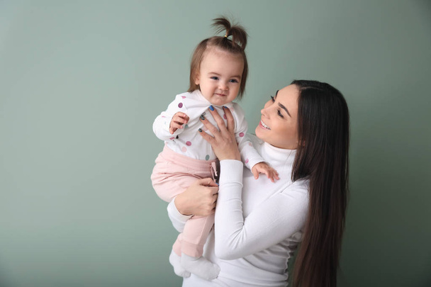 Young woman with her cute little daughter on color background - Photo, Image