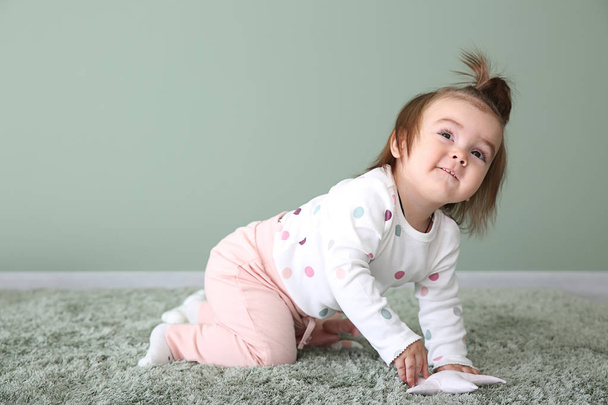 Cute baby girl on carpet near color wall - Photo, Image