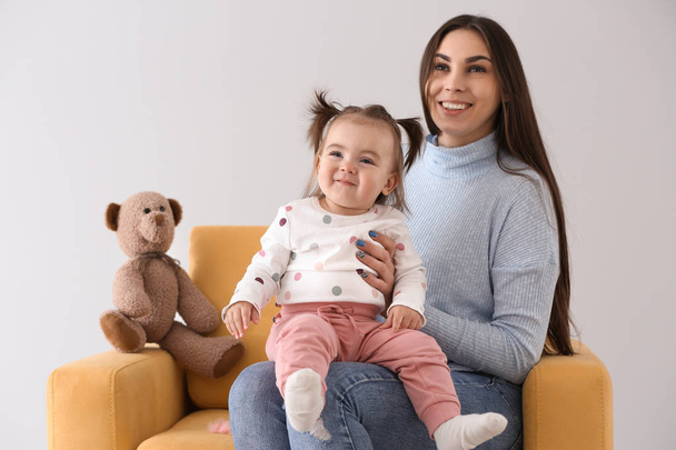 Young woman with her cute little daughter sitting in armchair - Foto, immagini