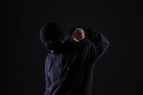 Bandido com arma no fundo escuro
 - Foto, Imagem