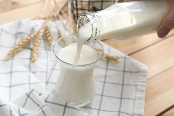 Nalití čerstvého mléka z láhve do sklenice na stole - Fotografie, Obrázek