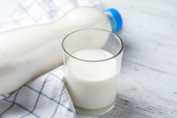 Стекло и бутылка свежего молока на деревянном столе
 - Фото, изображение
