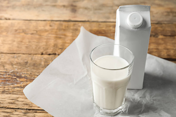 Sklenice čerstvého mléka a krabici pack na dřevěný stůl - Fotografie, Obrázek