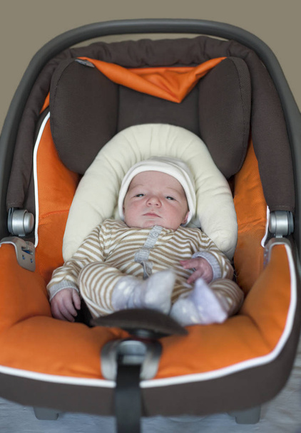 Baby newborn at i-size baby car seat type. Few days-old baby at home - Foto, afbeelding