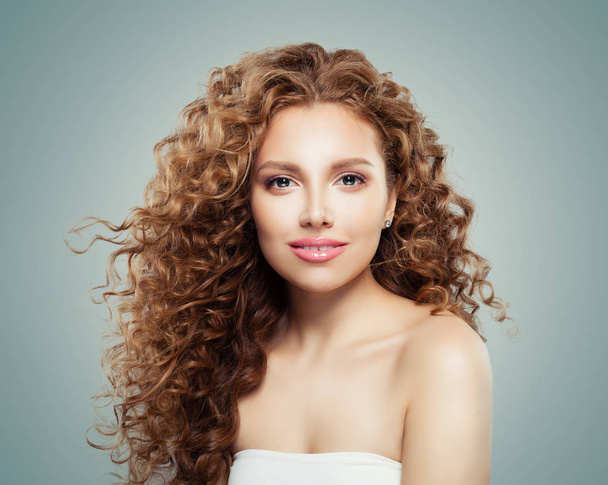 Beautiful smiling woman with healthy curly hair on gray background. Redhead girl - Zdjęcie, obraz