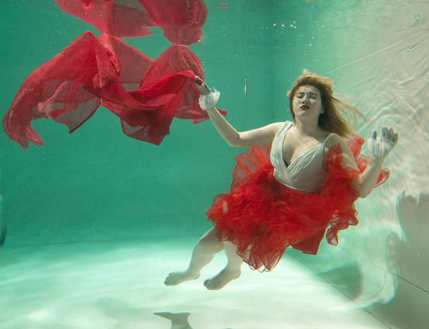 Hot Slim Caucasian Woman Posing Under water in beautiful clothes alone in the deep - Foto, Imagen