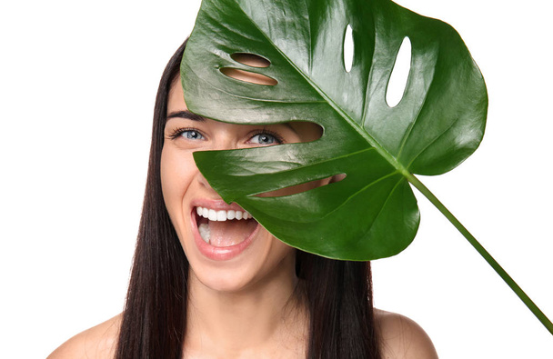Portrait of beautiful young woman with natural makeup and tropical leaf on white background - Photo, Image