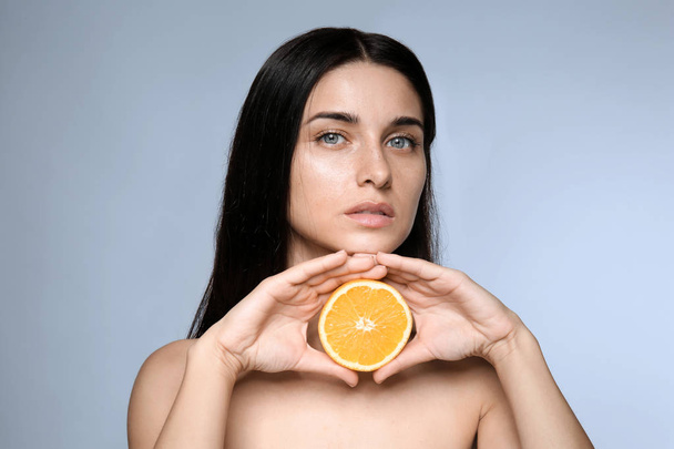 Portrait of beautiful young woman with natural makeup and orange on color background - Fotografie, Obrázek