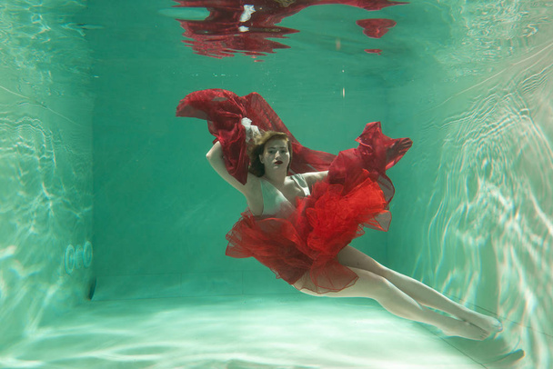Hot Slim Caucasian Woman Posing Under water in beautiful clothes alone in the deep - Φωτογραφία, εικόνα