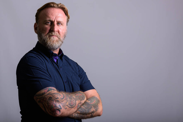 Portrait of mature bearded man with hand tattoos with arms crossed - Photo, Image