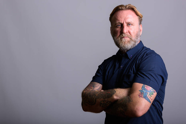 Portrét zralé vousatý muž s tetováním ruka s paží překřížené - Fotografie, Obrázek