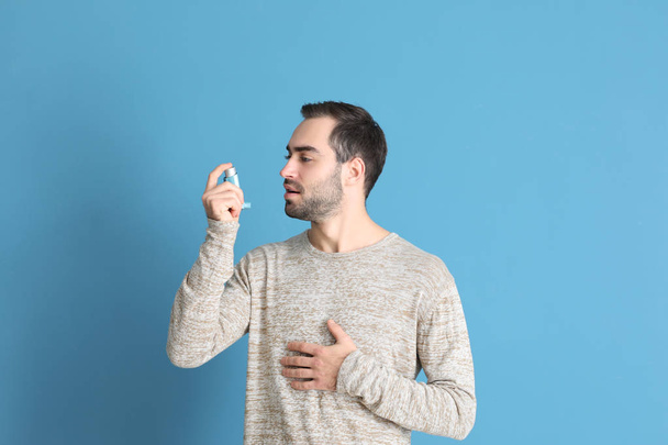 Young man with inhaler on color background - Photo, Image